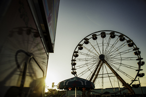 The Great New York State Fair Ferris wheel, one of two, rises above the fairgrounds at sunset. Because the fair is under new management this year with Wade Shows, the Ferris wheel is 20 feet shorter. Other attractions at the fair include concerts, exhibits and carnival games. 