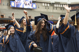 Syracuse University undergraduates wave to their friends and families in the audience as they take their seats for the ceremony.